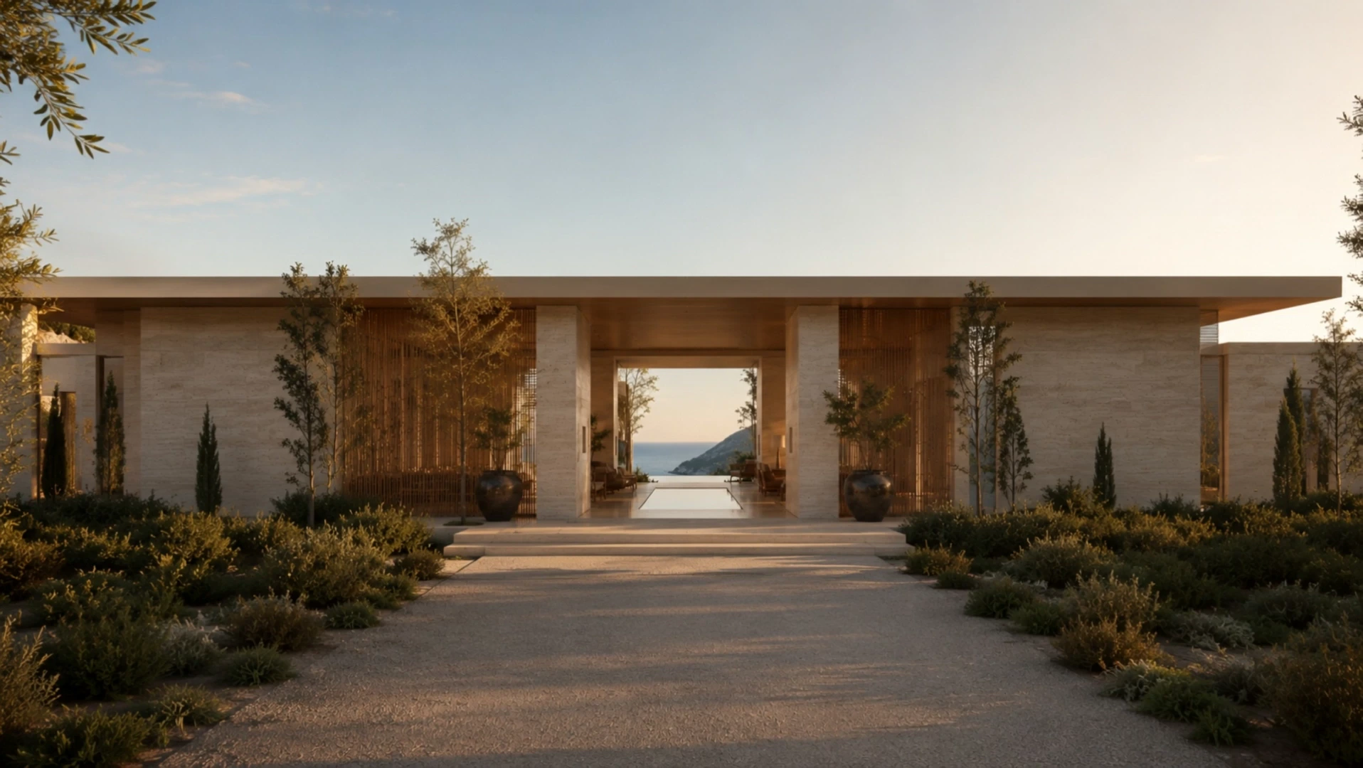 The travertine entrance of ALMARÉ at golden hour, framing a path through olive trees toward the sea.
